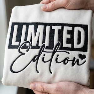 Puede incluir: Sudadera color crema con la inscripción bordada en negro "LIMITED Edition". La palabra "LIMITED" está en negrita, mientras que "Edition" está en cursiva, con un símbolo de corazón.