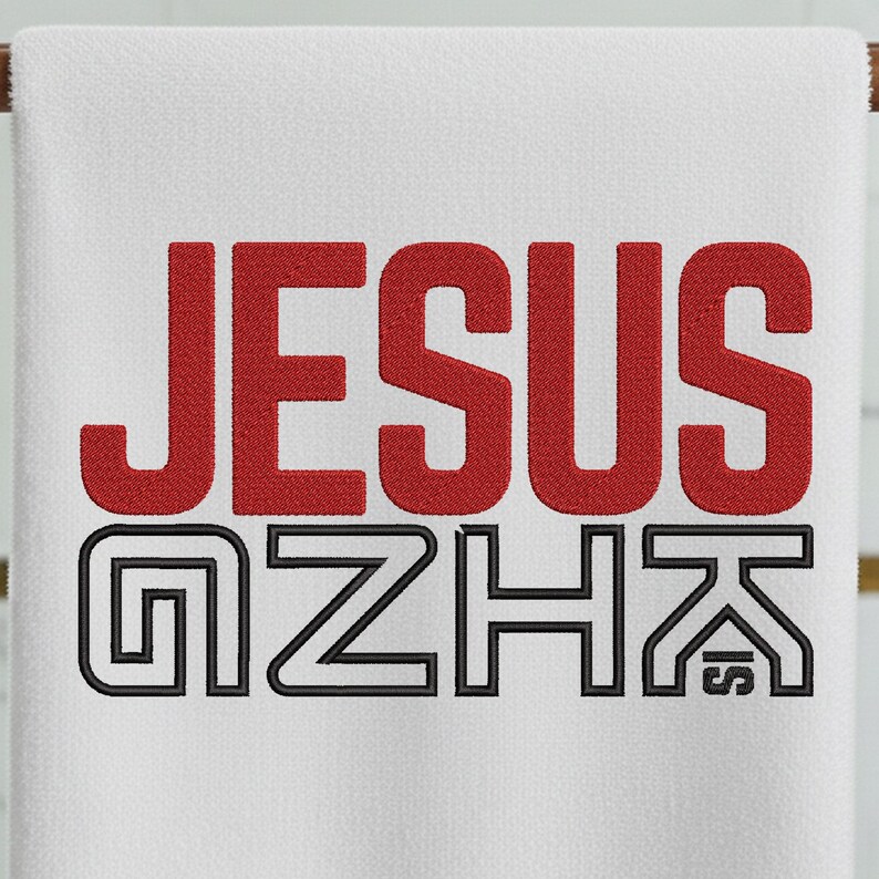 May include: White towel with the word "JESUS" in red, bold letters. Below it, the words "GZHK" are in black, outlined letters. The towel is hanging on a wooden rod.