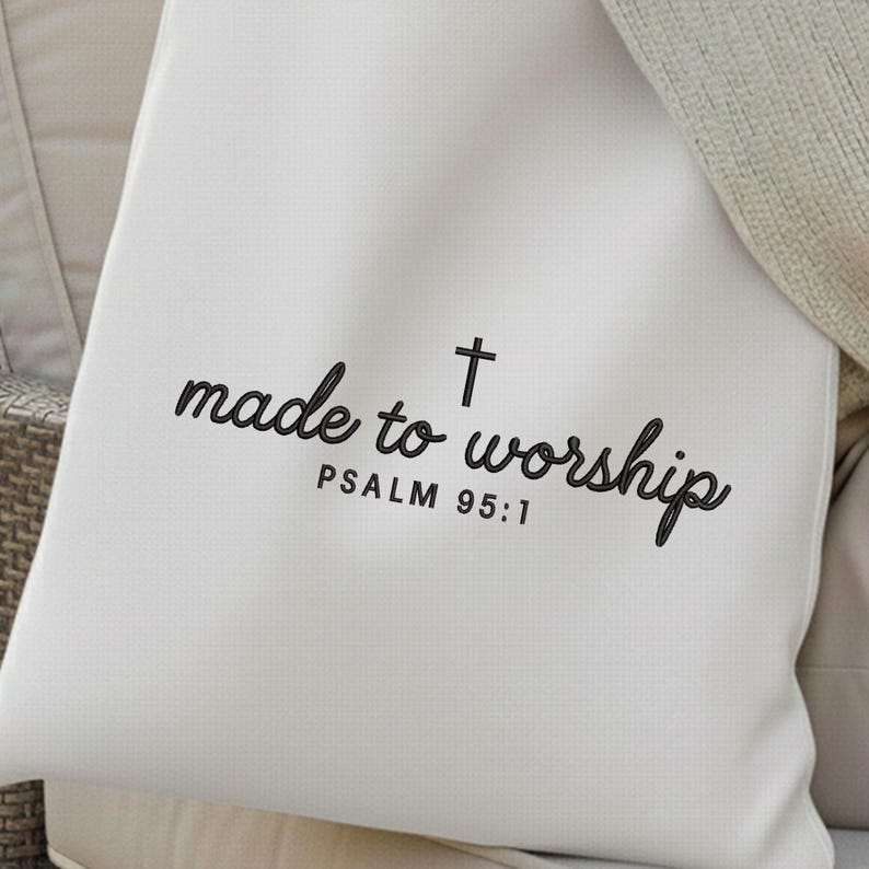 May include: Cream-colored pillow with the words "made to worship" and a cross symbol printed in black script. The text "PSALM 95:1" is printed below the main text. The pillow is on a neutral-toned surface.