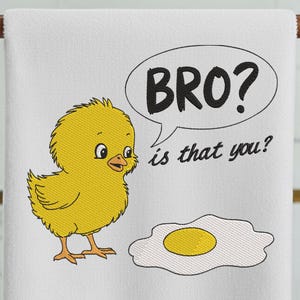 May include: White towel with an embroidered design featuring a yellow chick, a fried egg, and a speech bubble with the text "BRO? is that you?". The chick is looking at the egg with a curious expression.