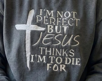 May include: Gray sweatshirt with white embroidered text and a cross. The text reads "I'M NOT PERFECT BUT JESUS THINKS I'M TO DIE FOR". The sweatshirt is a crew neck style.