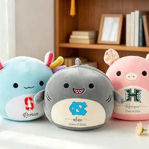 May include: Three plush toys: a light blue axolotl, a gray shark, and a pink pig. Each has a logo and name. The axolotl has a red tree logo and the name "Roman". The shark has a blue logo and the name "alice". The pig has a green logo and the name "Harper".
