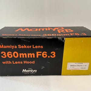 May include: A black and yellow rectangular cardboard box for a Mamiya RB Mamiya Sekor Lens 360mm F6.3 with Lens Hood. The box features orange text reading Mamiya RB, Mamiya Sekor Lens, 360mm F6.3, and with Lens Hood, with a white label on the side.