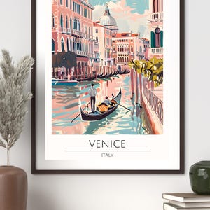 Op de afbeelding: Een ingelijste kunstafdruk met een kleurrijke kanaalsc&egrave;ne in Veneti&euml;, Itali&euml;. De afbeelding toont gondels, gebouwen en de tekst "VENICE ITALY". Het kunstwerk is in een vintage reisposterstijl.