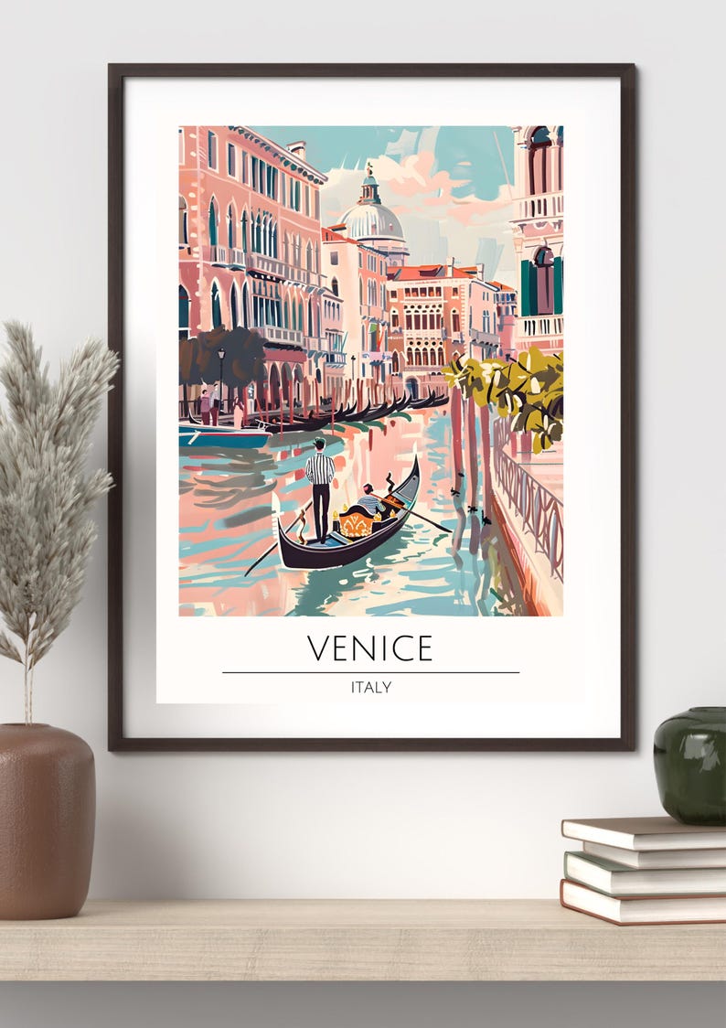 Op de afbeelding: Een ingelijste kunstafdruk met een kleurrijke kanaalsc&egrave;ne in Veneti&euml;, Itali&euml;. De afbeelding toont gondels, gebouwen en de tekst "VENICE ITALY". Het kunstwerk is in een vintage reisposterstijl.