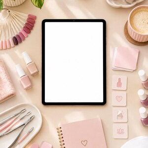 May include: A tablet with a blank white screen surrounded by nail care supplies including various pink and neutral nail polish bottles, a color swatch fan, metal cuticle tools, a spiral-bound pink notebook with a heart, and a white nail lamp.
