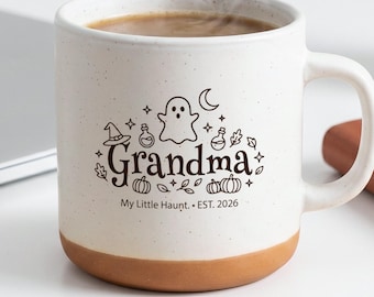 May include: A speckled off-white ceramic mug with a terracotta base. The front features black line art of a ghost, pumpkins, a witch hat, and potions, with the text "Grandma" and "My Little Haunt. EST. 2026" printed in a decorative font.