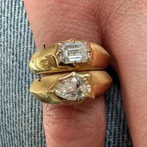 Peut inclure: Deux bagues en or, l'une avec un diamant taille émeraude et l'autre avec un diamant en forme de poire. Les bagues sont serties dans une bande en or brossé.