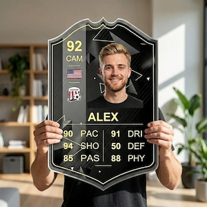 May include: A black and gold soccer card with a photo of a smiling man named Alex. The card shows the number 92, the letters CAM, and player stats. The American flag and a soccer team logo are also visible.