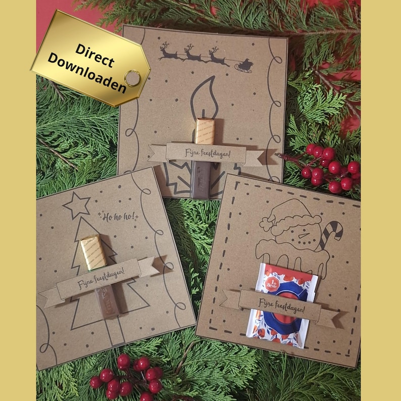 May include: Three festive Christmas cards on a bed of greenery. Each card is brown with a different holiday design: a candle, a Christmas tree, and a snowman. Each card has a banner with text and a small treat attached.