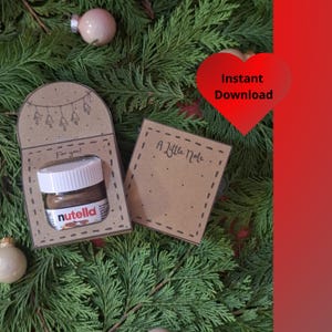 Pode incluir: Um pequeno frasco de Nutella numa manga decorativa de papel castanho com o texto "For you!" e um pequeno cartão que diz "A Little Note". O fundo é composto por ramos de sempre-vivas e ornamentos. Um coração vermelho com as palavras "Instant Download" está no canto superior direito.