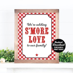 May include: A printable sign with a red and white gingham background. The sign says "We're adding S'MORE LOVE to our family!" with a red star below the text. The sign is framed in a brown wood frame. The text "Instant Download PURCHASE & PRINT TODAY!" is in a circle on the right side of the sign. The text "PURCHASE INCLUDES 8"X10" AND 5"X7" SIGNS TEXT IS NOT EDITABLE" is below the sign.