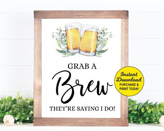 May include: A printable sign with a wooden frame and a white background. The sign features two cartoon beer mugs with a green leafy design and the text "Grab a Brew They're Saying I Do!"  The sign also includes the text "Instant Download Purchase & Print Today".