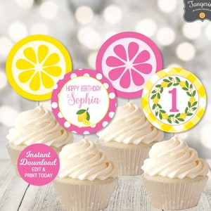 May include: Printable cupcake toppers featuring a lemon theme. The toppers include a yellow lemon slice, a pink lemon slice, a pink and white polka dot circle with the text "Happy Birthday Sophia", a yellow and white gingham circle with a green wreath and the number "1" in pink, and a circle with the text "Instant Download EDIT & PRINT TODAY".