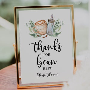 May include: A gold-framed sign with a white background and black text that reads "Thanks for bean here. Please take one". The sign features a watercolor illustration of a coffee cup and a baby bottle.