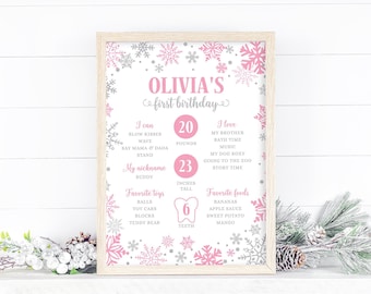 Può includere: Un cartello di primo compleanno stampabile rosa e argento con fiocchi di neve e il testo "Olivia's first birthday". Il cartello elenca l'età, l'altezza e le cose preferite del bambino.