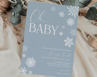 May include: A light blue baby shower invitation with white snowflakes and the text "Oh Baby" in a script font. The invitation includes details for the event, including the date, time, location, and RSVP information. The text also mentions that gifts can be registered at Target and Amazon.