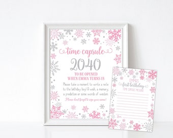 May include: Pink and silver snowflake design time capsule sign with the text "time capsule 2040" and instructions to be opened when the person turns 18. A matching card with lined space for writing a message.