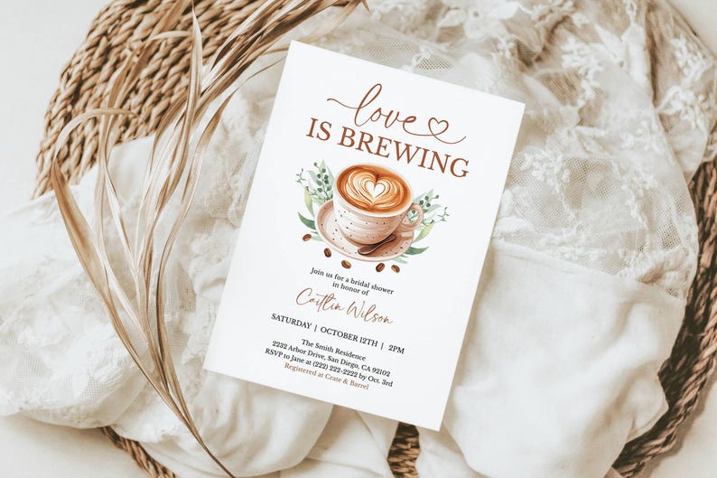 K&ouml;nnte beinhalten: Eine wei&szlig;e Einladungskarte mit dem Text "love IS BREWING" und einer Kaffeetassen-Illustration. Die Karte ist f&uuml;r eine Brautparty zu Ehren von Caitlin Wilson, mit Datum, Uhrzeit und Ortsangaben. Die Karte liegt auf einem wei&szlig;en Spitzentuch.