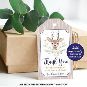 May include: An illustration of a brown and white deer with floral accents on a beige woodgrain background. The text "Thank You" is printed in purple with the words "For showering our little deer with love!" and "Love, Chastie & Jagon" printed below. A blue circle with the text "Sold Separately FIND LINK IN ITEM DETAILS" is in the top right corner.