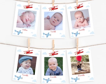 May include: Six photos of a baby boy at different ages, from newborn to 12 months. Each photo is framed with a red airplane and blue clouds. The photos are hung on a string with clothespins. The ages are written below each photo: newborn, 1 month, 2 months, 4 months, 6 months, and 12 months.