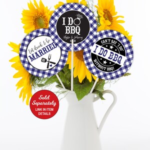 May include: Three 5-inch round centerpieces with blue and white gingham patterns. The centerpieces feature text that says "Eat drink & be married", "I do BBQ Alyssa & Johnny 3-21", and "Can't say I do I do BBQ without BBQ!"