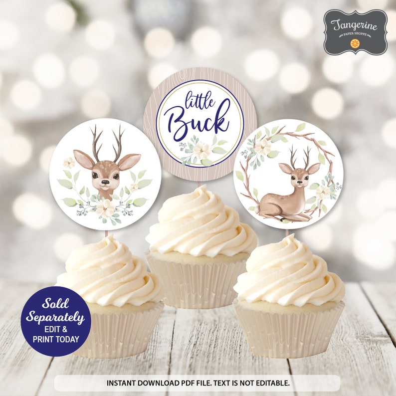 May include: Cupcakes with toppers featuring a deer theme. The toppers have deer illustrations and the text "little Buck". The cupcakes are decorated with white frosting. The image also includes the text "Sold Separately, Edit & Print Today".