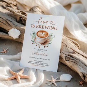 K&ouml;nnte beinhalten: Eine Einladung zur Brautparty mit dem Text "love IS BREWING" und einer Kaffeetassen-Illustration. Die Einladung enth&auml;lt Details f&uuml;r Caitlins Wilson's Party, vor einem Strandhintergrund mit Muscheln und Seesternen.
