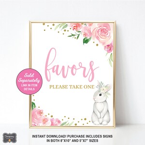 May include: A pink and gold printable sign with the text "favors please take one" and a watercolor illustration of a bunny rabbit with a floral crown. The sign is decorated with pink flowers and gold glitter.