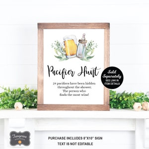 May include: A printable sign for a baby shower game. The sign is white with black text and a watercolor illustration of a beer mug and a baby bottle. The text reads "Pacifier Hunt" and "24 pacifiers have been hidden throughout the shower. The person who finds the most wins!"