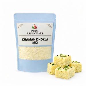 Puede incluir: Una bolsa azul claro de Pure Essentials Khaman Dhokla Mix junto a cuatro trozos cuadrados de dhokla preparado. El dhokla es amarillo con semillas negras y hierbas verdes encima. La bolsa tiene una etiqueta blanca con texto.