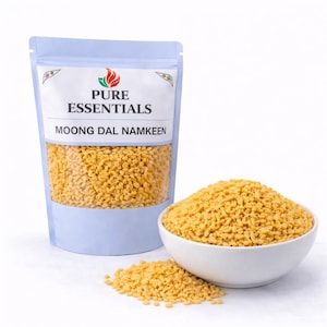 May include: A clear plastic bag of Moong Dal Namkeen next to a white bowl filled with the same snack. The bag has a light blue border and the text "PURE ESSENTIALS" and "MOONG DAL NAMKEEN".