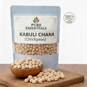 Può includere: Una confezione di Kabuli Chana (ceci) di Pure Essentials, con un sigillo 100% naturale. La confezione azzurra mostra i ceci. Una ciotola di legno e un piccolo mucchio di ceci sono su un tagliere di legno.