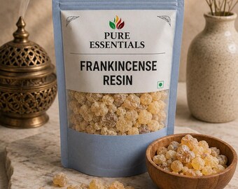Könnte beinhalten: Ein hellblauer Standbeutel mit der Aufschrift Pure Essentials Frankincense Resin, gefüllt mit kleinen, durchscheinenden, goldbraunen Harzstücken. Eine Holzschale mit demselben Harz steht daneben, lose Stücke liegen auf der Oberfläche.