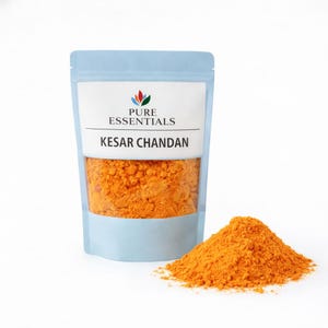 May include: A light blue pouch of Kesar Chandan powder with the Pure Essentials logo. A pile of orange powder sits next to the pouch. The pouch is filled with the same orange powder.