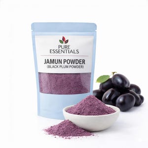 Könnte beinhalten: Eine Packung Jamun-Pulver (Schwarzpflaumenpulver) mit einem weißen Etikett und dem Aufdruck "Pure Essentials". Eine kleine weiße Schüssel und ein Haufen des violetten Pulvers befinden sich vor der Packung. Rechts befindet sich ein Haufen frischer schwarzer Pflaumen.