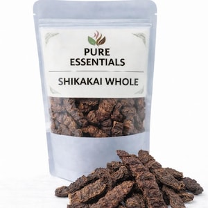 Puede incluir: Una bolsa transparente de Shikakai entero marrón, con el texto "PURE ESSENTIALS SHIKAKAI WHOLE". Un pequeño montón del producto está delante de la bolsa. El producto parece ser vainas secas.