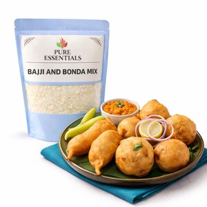 May include: A package of "Pure Essentials" Bajji and Bonda Mix next to a plate of fried snacks. The plate includes round and oblong golden-brown fritters, green peppers, and a small bowl of orange chutney. Garnished with onion and lemon slices.