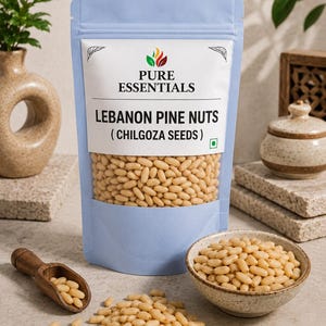 以下が含まれることがあります： Pure Essentials Lebanon Pine Nuts (Chilgoza Seeds)とラベルが貼られた水色のスタンドパウチに、ベージュ色の松の実が入っています。小さな木製のスクープと斑点のある陶器のボウルにも同じ松の実が入っており、表面にもいくつか散らばっています。