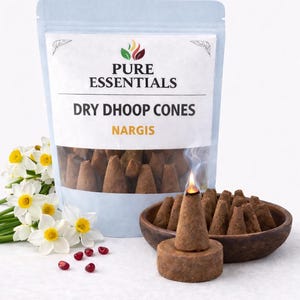 Könnte beinhalten: Eine Packung brauner, trockener Dhoop-Kegel mit der Aufschrift "Pure Essentials" und "Nargis". Ein angezündeter Kegel gibt Rauch ab, mit einer kleinen Holzschale und Blumen in der Nähe. Die Kegel sind hellbraun.