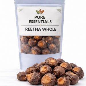 May include: A transparent pouch filled with brown Reetha whole soap nuts, with a pile of nuts in front. The pouch has a white label with the text "PURE ESSENTIALS" and "REETHA WHOLE".