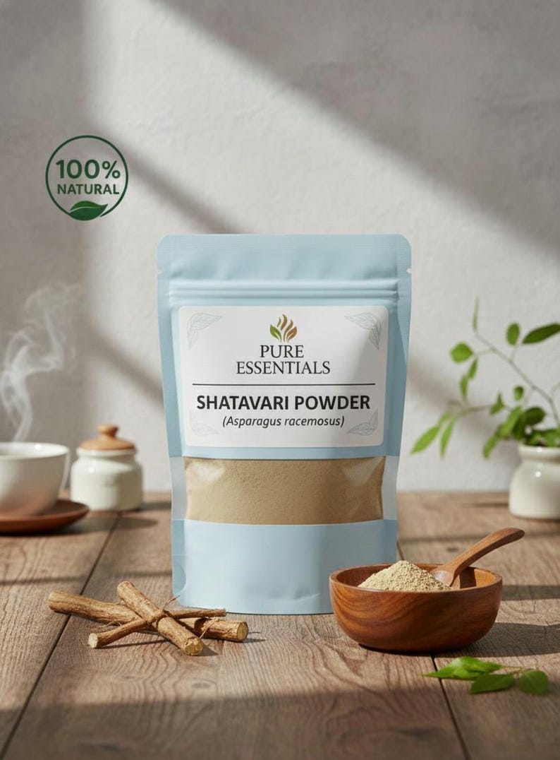 Puede incluir: Una bolsa azul claro de polvo de Shatavari (Asparagus racemosus) est&aacute; sobre una superficie de madera. Un cuenco de madera con polvo y una cuchara est&aacute;n a la derecha. Las palabras "Pure Essentials" y "100% Natural" son visibles.