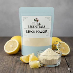 Peut inclure: Un sachet bleu clair avec l'inscription "PURE ESSENTIALS LEMON POWDER", un bol en verre transparent rempli de poudre de citron et des citrons frais. L'image comprend un autocollant "100% NATURAL" et des tranches de citron sur une surface en bois.