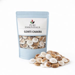 Puede incluir: Una bolsa azul claro con la etiqueta "PURE ESSENTIALS GOMTI CHAKRA" llena de pequeñas piedras en espiral, de color beige y blanco. Un montón de piedras similares descansa frente a la bolsa, todo sobre un fondo blanco.