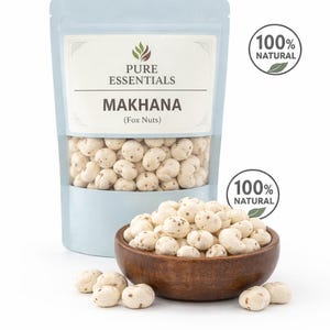 以下が含まれることがあります： Pure EssentialsのMakhana（フォックスナッツ）のパッケージと、同じナッツが入った木製のボウル。パッケージは水色で、「Makhana（フォックスナッツ）」の文字が入っています。「100％ナチュラル」のシールも表示されています。