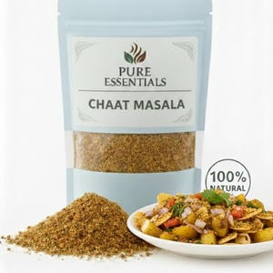 May include: A light blue pouch of Pure Essentials Chaat Masala with a pile of the spice in front. A small white plate of chaat is to the right, and a "100% Natural" sticker is on the right.