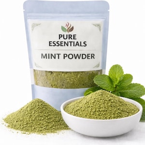 May include: A bag and bowl of green mint powder with fresh mint leaves. The bag is labeled "Pure Essentials Mint Powder". The powder is a vibrant green color, and the image is set against a white background.