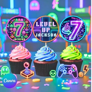 May include: Three cupcakes with colorful frosting and decorative toppers. The toppers feature the number 7, the text "Level Up Jackson", and a gaming theme. Neon game controllers and other gaming elements are scattered around the cupcakes.