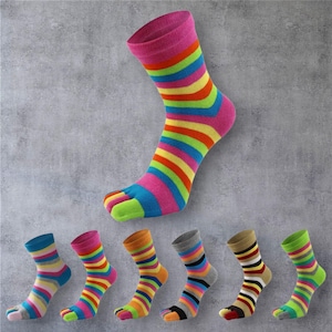 Op de afbeelding: Een verzameling kleurrijke teensokken met strepenpatronen. De sokken hebben een apart compartiment voor elke teen en zijn verkrijgbaar in verschillende kleurencombinaties, waaronder blauw, roze, oranje en groen. De sokken worden gepresenteerd tegen een grijze achtergrond.