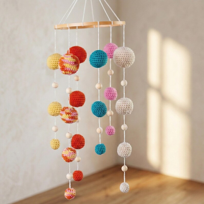 May include: A colorful crochet mobile with a wooden ring and hanging spheres. The spheres are in various colors, including red, yellow, pink, and blue. Wooden beads are interspersed between the spheres. This decorative mobile is suitable for a nursery or children's room.